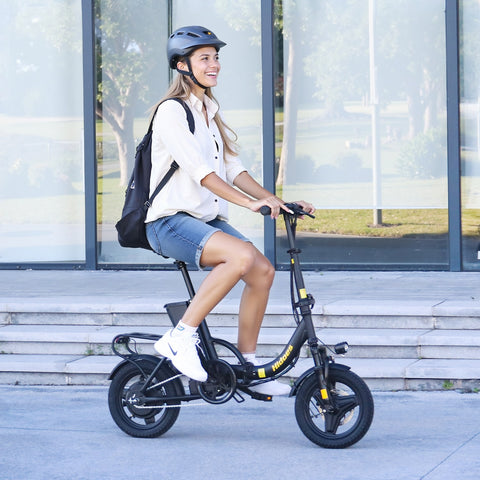 Woman riding a black Hidoes C5 electric bike in an urban setting. 